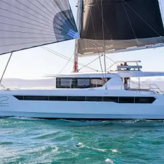 Un catamarano Leopard 52 con vele spiegate naviga su acque turchesi, con montagne sullo sfondo.