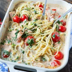 Herzhafte Lachs Spinat Pasta in cremiger Sauce mit Kirschtomaten, serviert in einer Auflaufform.