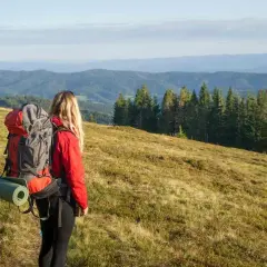 Kobieta z plecakiem na szlaku, zastanawia się, co to jest elastomultiester, gdy podziwia górski krajobraz.