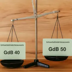 Eine Waage zeigt zwei Schwerbehindertenausweise: GdB 40 und GdB 50. Dies illustriert den **diabetes behinderungsgrad**.
