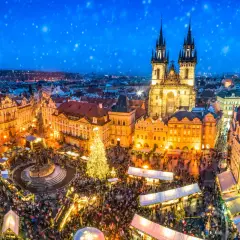 Tłoczny jarmark bożonarodzeniowy na Rynku Staromiejskim w Pradze. Śnieg prószy nad oświetloną choinką i tłumami ludzi. To magiczne święta w Czechach.