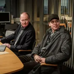 Två män vid ett bord, en äldre med laptop och en yngre med keps. Kanske planerar de nästa Beck 51-fall.