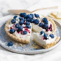 Tarta z kremem z białej czekolady, udekorowana borówkami i wiórkami białej czekolady. Wygląda pysznie!