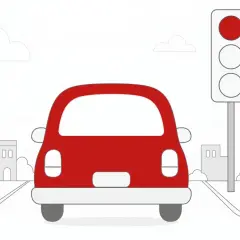 Czerwony samochód zatrzymał się przed sygnalizatorem świetlnym. Czerwone światło oznacza stop, aby uniknąć mandatu.