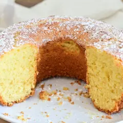 Una ciambella soffice, cosparsa di zucchero a velo, attende di essere gustata. La sua consistenza invitante promette un momento di puro piacere.