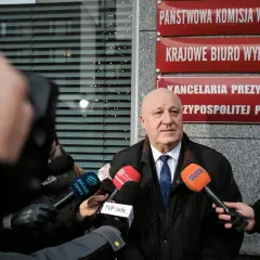 Mężczyzna przed Państwową Komisją Wyborczą, otoczony mikrofonami, mówi o prawdzie o finansowaniu kampanii PiS i decyzjach PKW o odebraniu dotacji.