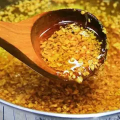 Holzschöpfkelle hebt goldbraun angebratenen Knoblauch aus heißem Öl. Knoblauch anbraten oder nicht? Hier die Antwort!
