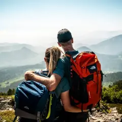 Couple en randonnée, admirant le panorama des montagnes de la Grande Ardèche. Sacs à dos orange et bleus, vue imprenable.