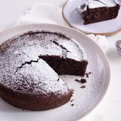 Gâteau au chocolat saupoudré de sucre glace, une part coupée. Idéal pour savoir par quoi remplacer le beurre dans un gâteau au chocolat.