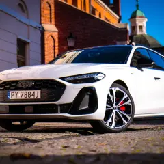 Białe Audi A5 na brukowanej ulicy, z zabytkową architekturą w tle. Zastanawiasz się nad jego spalaniem?