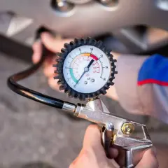 Manómetro de presión de neumáticos conectado a la válvula de una rueda. Aprende como saber la presion de las ruedas del coche para mayor seguridad.