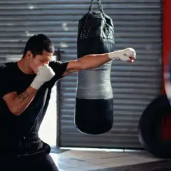 A boxer trains in a gym, practicing the sweet science of boxing with a punching bag.