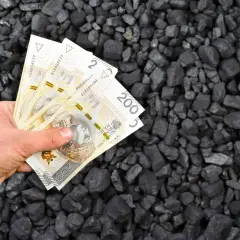 Dłoń trzyma polskie banknoty na tle węgla. Czy wspólnoty mieszkaniowe dostaną dodatek węglowy?
