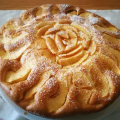 Una deliziosa torta di mele senza glutine, decorata con fettine di mela a forma di rosa e spolverata di zucchero a velo.