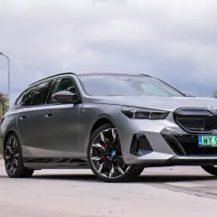 Srebrne BMW i5 na tle pochmurnego nieba, z widocznymi felgami i tablicą rejestracyjną.