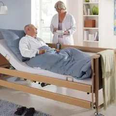 Opieka nad chorym członkiem rodziny: pielęgniarka podaje posiłek leżącemu w łóżku pacjentowi.