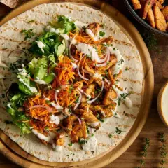 Pyszny kebab z kurczakiem, warzywami i obficie polany kremowym sosem do kebaba.