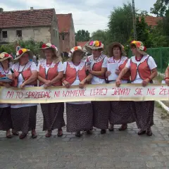 Kobiety w ludowych strojach trzymają transparent z napisem "Ni to sprzedać, ni wymienić, lepiej Janku się nie żenić" - śmieszne teksty na bramy weselne.
