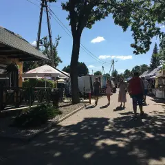 Tleń atrakcje: ludzie spacerują po rynku, podziwiając stoiska z rękodziełem i lokalnymi produktami.