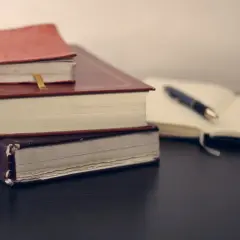 Stos książek i otwarty notatnik z piórem. Wśród nich mądrość syracha cytaty, czekająca na odkrycie.