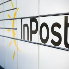 Czy do paczkomatu InPost trzeba drukować etykietę? Zbliżenie na białą obudowę paczkomatu z czarnym logo InPost i żółtym symbolem.