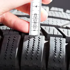 Mesure de la profondeur des sculptures d'un pneu pour estimer sa durée de vie. La règle indique environ 1 cm.
