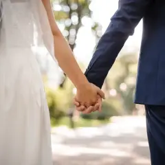 Para młoda trzymająca się za ręce, w tle park. To idealny moment na urlop okolicznościowy.