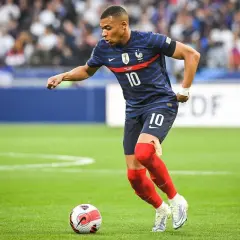 Kylian Mbappé w niebieskiej koszulce z numerem 10, w czerwonych getrach, wykonuje najszybszy sprint w piłce nożnej, prowadząc piłkę.