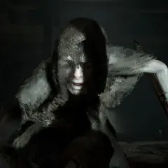 Przerażająca postać z kapturem, z wykrzywioną twarzą i białymi oczami, gotowa do ataku. Klasyczny horrory jumpscare.