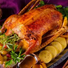 Eine goldbraune Gans auf dem Grill, garniert mit Trauben, Orangen und Sternanis. Perfekt für ein festliches Mahl.