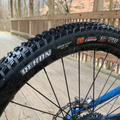 Maxxis Rekon tire on a wet wooden bridge. These tires are great for trail riding, offering excellent grip and durability.