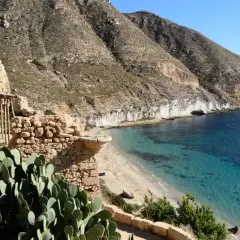 Ruinas de la hippie comuna Cala San Pedro, Almería, con mar turquesa y montañas.