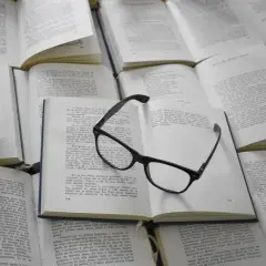 Lunettes posées sur des livres ouverts. Ces figures de style servent à enrichir le texte et à rendre la lecture plus captivante.