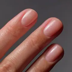 Zbliżenie na dłonie z eleganckimi, różowymi paznokciami z subtelnym połyskiem.