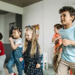 Dzieci tańczą i bawią się w sali, wyrażając emocje poprzez ruch.