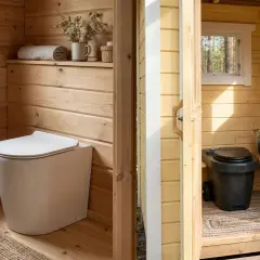 Två toaletter utan avlopp i trästugor. En vit, modern toalett i en ljus trästuga med fönster. En svart, enklare toalett i en gul stuga med en hink och toalettpapper.