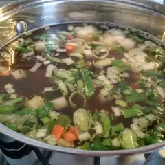 Gotowanie zupy jarzynowej z mrożonek. W garnku bulgocze aromatyczny wywar z warzywami.