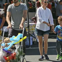 Natalie Portman z dziećmi na targu. Syn trzyma ją za rękę, a w wózku widać pluszowego misia i balony.