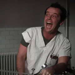 Jack Nicholson w roli McMurphy'ego w "Locie nad kukułczym gniazdem" obsada, szaleńczo krzyczy w szpitalnym ubraniu.