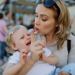 Bambina piange mentre la madre, forse afflitta da depressione, cerca di calmarla. Gli effetti della madre depressa sui figli adulti sono complessi.