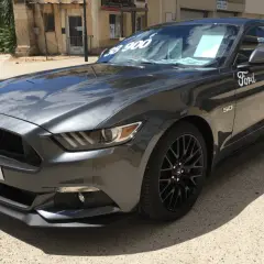 Szary Ford Mustang GT 5.0 z ceną 38 900 na szybie, gotowy do jazdy.