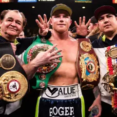 Canelo Alvarez, surrounded by his team, proudly displays his championship belts, a testament to his incredible record.