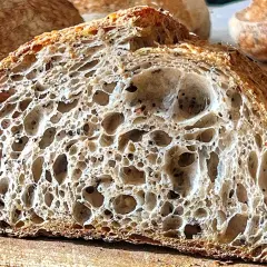 Fetta di pane con lievito madre, alveolatura perfetta e crosta dorata. Un capolavoro artigianale.