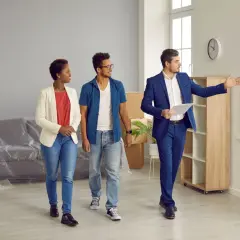 Un agent immobilier présente un appartement à un couple. Ils consultent leur checklist visite appartement.