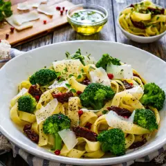 Pyszny obiad z brokułem: tagliatelle z zielonymi różyczkami, suszonymi pomidorami i parmezanem.