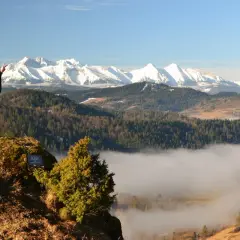 Kobieta na skale z widokiem na góry i morze mgły. To piękne lesnicke sedlo, idealne na wędrówkę.