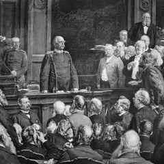 Bismarck steht im Mittelpunkt einer Versammlung, die den Berliner Vertrag darstellt. Männer in Anzügen und Uniformen diskutieren.