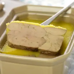 Tranche de foie gras au porto blanc, servie dans un plat en céramique avec une cuillère.