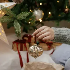 Ręka zdejmuje ozdobę z choinki. Czas pomyśleć, kiedy zdjąć dekoracje świąteczne.