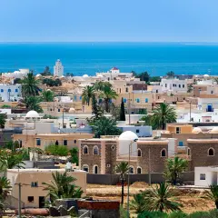 Piękne, białe domy z niebieskimi okiennicami i palmami na tle błękitnego morza. Idealna pogoda Djerba.